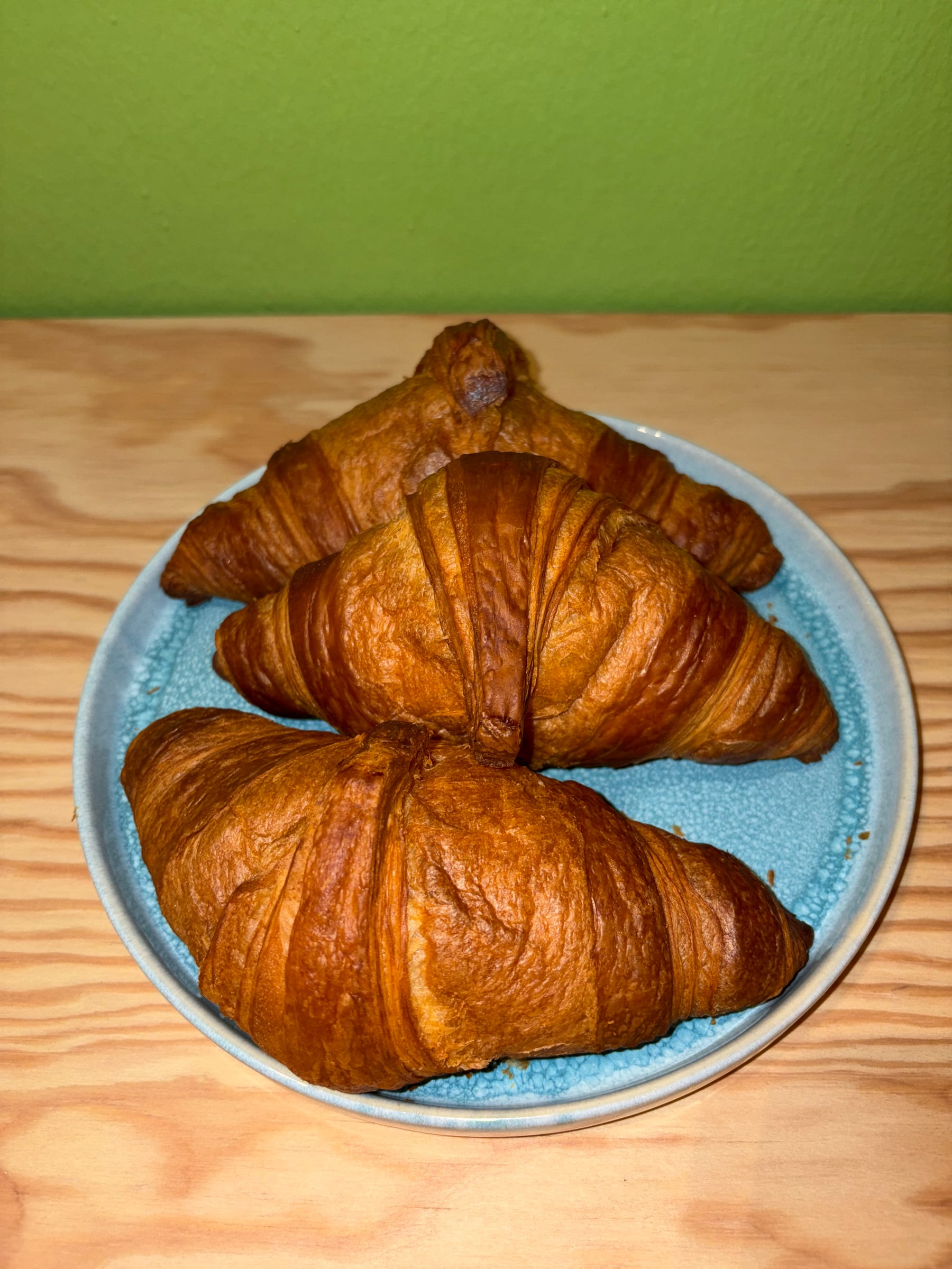 Drei frisch gebackene Croissants auf einem Teller