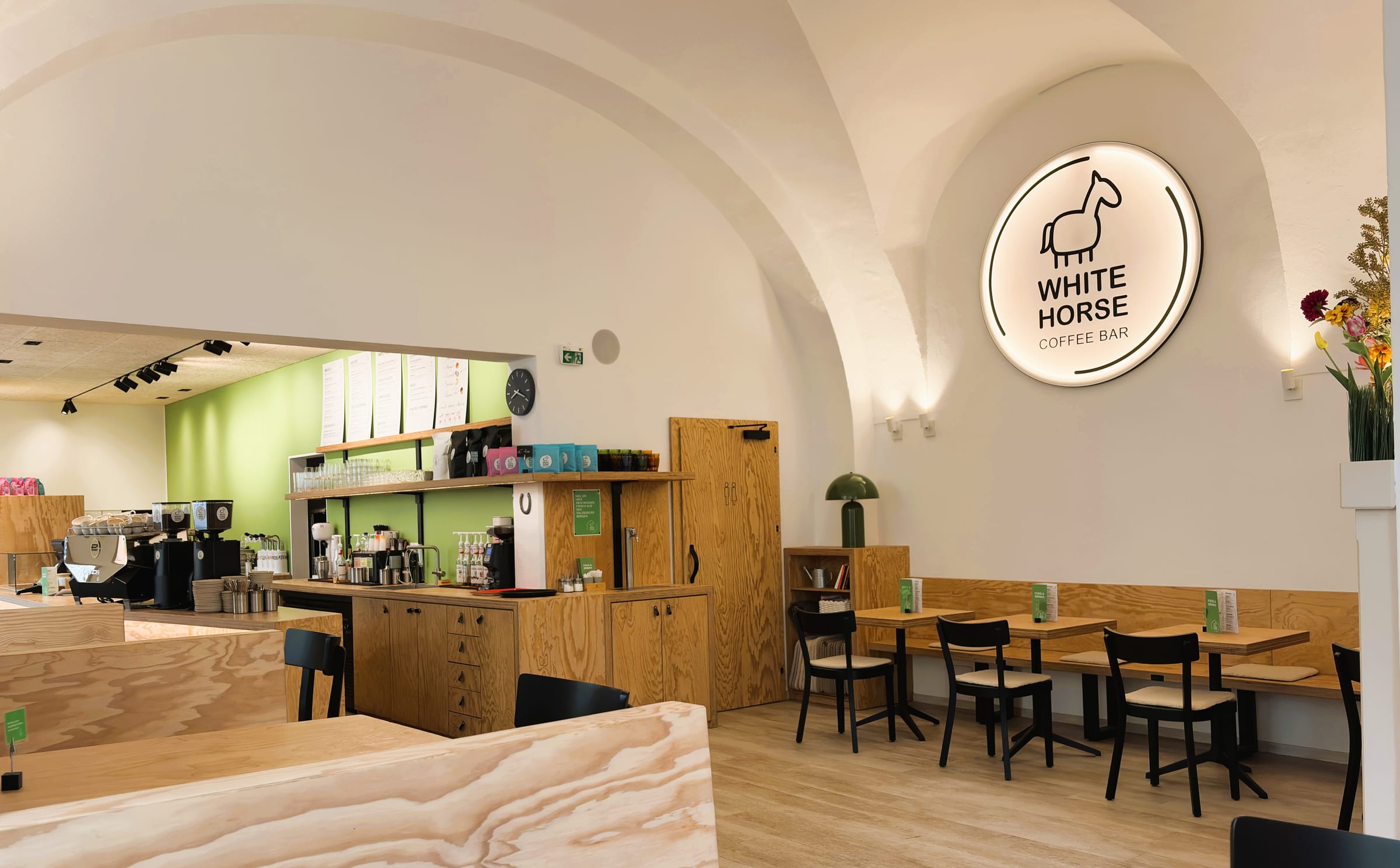 Weiter Blick durch den Gastraum mit Theke, Sitzbänken und beleuchtetem White-Horse-Logo-Schild an der Wand