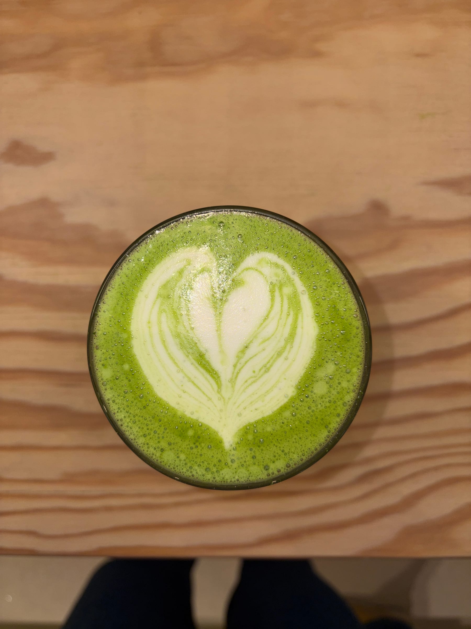 Matcha Latte mit Herz-Latteart auf einem Holztisch